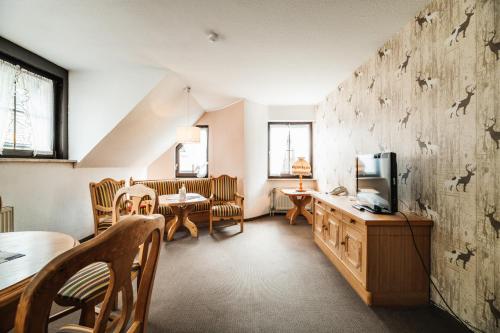 a living room with a tv and a table and chairs at Landhotel Alte Aue in Altenau