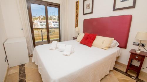 een slaapkamer met een groot wit bed en een raam bij Marina del Castillo 124 in Manilva