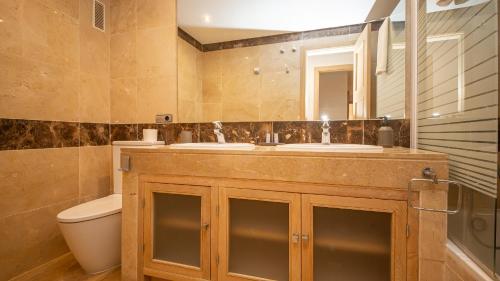 een badkamer met 2 wastafels, een toilet en een spiegel bij Marina del Castillo 124 in Manilva
