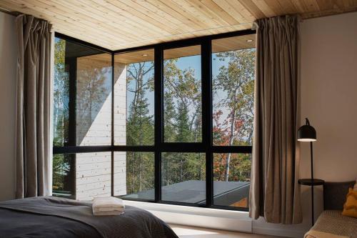 a bedroom with a large window with a view at Le Ruisseau: luxurious villa in Charlevoix. in La Malbaie