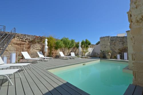 a swimming pool with white lounge chairs and a swimming pool at Villa Rocce Bianche in Favignana
