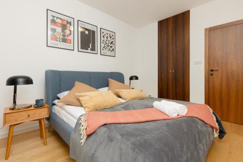 a bedroom with a blue bed with pillows and a table at Trendy & Spacious 3-room Apartament Warsaw Wilanów by Renters in Warsaw