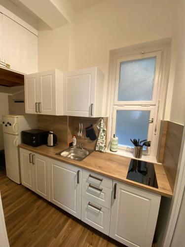 eine Küche mit weißen Schränken, einem Waschbecken und einem Fenster in der Unterkunft Prahabel - C10 in Prag