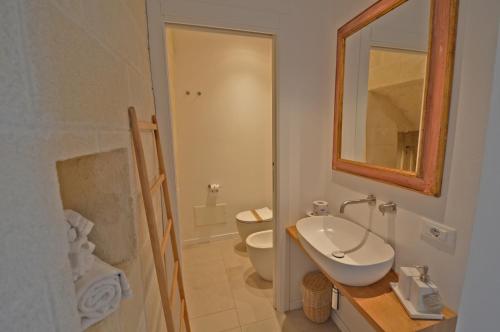 a bathroom with a toilet and a sink and a mirror at Villa Rocce Bianche in Favignana