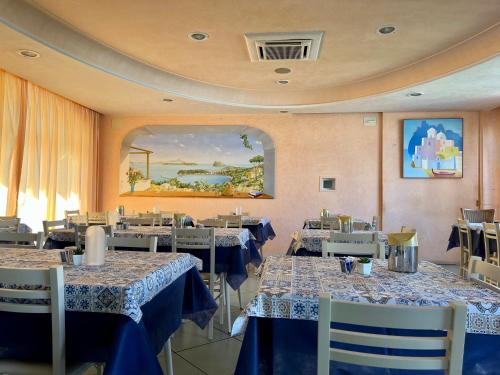 een restaurant met tafels en stoelen met blauwe en witte tafelkleden bij Hotel Rosetta in Ischia