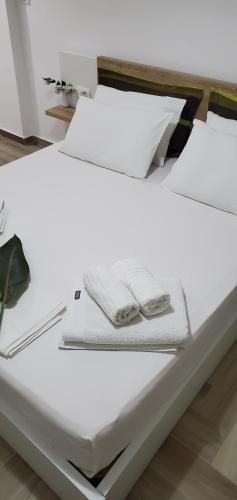 a white bed with two towels on top of it at The Hill Apartment in Sarandë