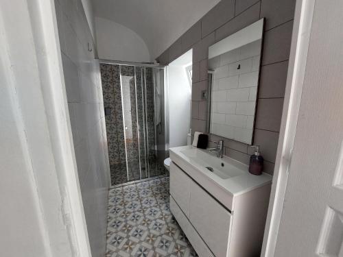 a white bathroom with a sink and a shower at Casa Ibaía, típica e acolhedora no centro de Olhão in Olhão