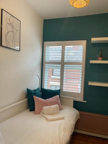 a bed in a room with a green wall at Hoole House- Bright and modern 2 bedroom house, close to Chester train station and the City Centre in Chester