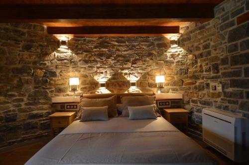 a bedroom with a bed in a stone wall at Hotel Rural El Portón de Murillo in Broto