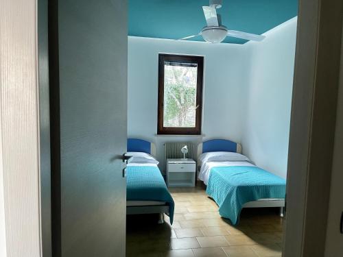 two beds in a room with blue walls and a window at Casa Tuly 1 in Brenzone sul Garda