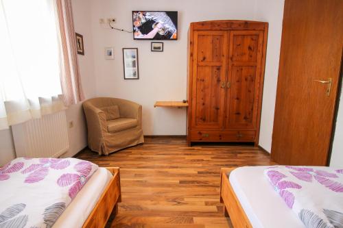 a bedroom with two beds and a chair and a door at Haus Kinspergher in Innsbruck