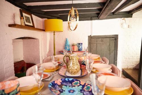 a table with plates and glasses and a vase on it at The Old Stout House - interior designed, converted 1700s Inn in Rye