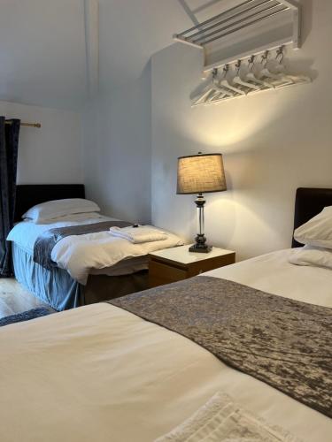 カーディフにあるMayfair Guest Houseのベッド2台、ランプ1台が備わる客室です。