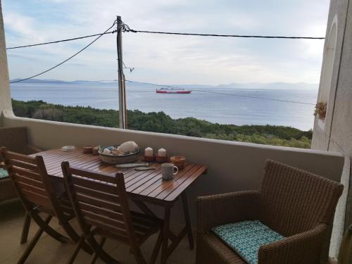 a table on a balcony with a view of the water at Indigo in Rafina