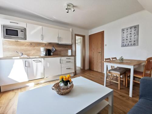 uma cozinha com armários brancos e uma mesa com flores em Ferienhaus Strandlust em Baltrum