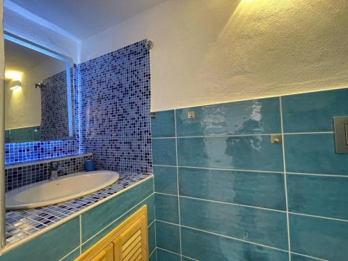 Baño de azulejos azules con lavabo y espejo en Nuovo Bilocale Frontemare, en Varazze