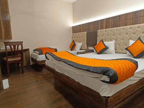 a bedroom with two beds with orange pillows at Hotel Batra Home Nizamuddin in New Delhi