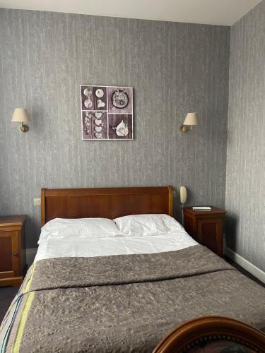 a bedroom with a bed with two nightstands and two lamps at Hotel La Poularde in Gien