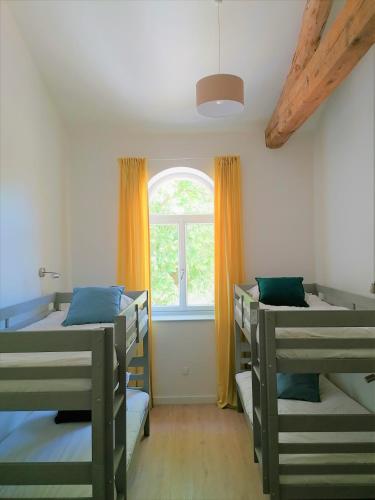 une chambre avec trois lits superposés et une fenêtre dans l'établissement Gîte de l'Abbé 8 à 10 personnes, à Lempaut