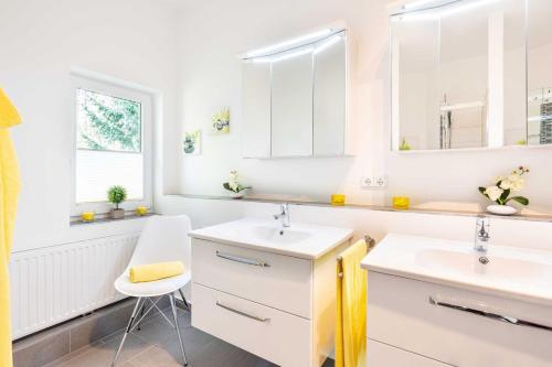a white bathroom with two sinks and a chair at Gerhart-Hauptmann-Strasse 1a Ferienhaus Waldblick in Kolpinsee