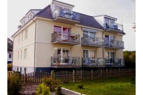 a large white house with balconies and a fence at Inselhaus Karlstrasse 6a Ferienwohnung 4 in Stubbenfelde