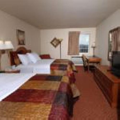 a large bedroom with two beds and a television at All American Inn & Suites Branson in Branson
