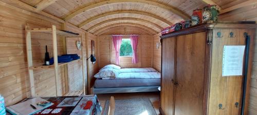 a small room with a bed in a wooden cabin at Urlaub im Bauwagen in Mörlenbach