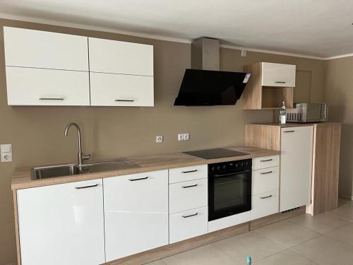 eine Küche mit weißen Schränken, einer Spüle und einer Mikrowelle in der Unterkunft Moderne luxuriöse Wohnung in Lüdenscheid