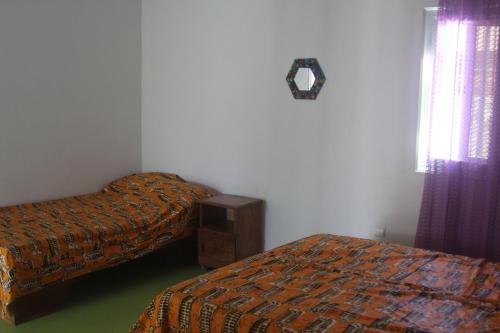 2 Betten in einem Zimmer mit lila Vorhängen in der Unterkunft Le Margouillat 