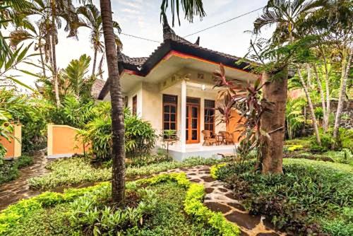 a house in the middle of a garden with palm trees at Kaia Lovina Guest House in Lovina