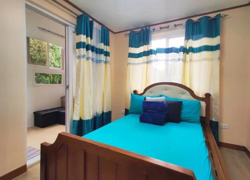 um quarto com uma cama com lençóis azuis e uma janela em Zenmist Properties- 2 Bedroom Deluxe em Baguio