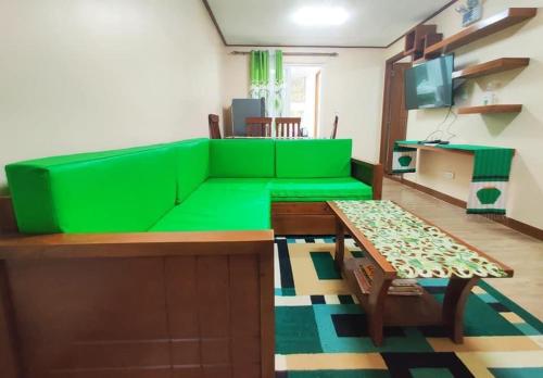a living room with a green couch and a table at Zenmist Properties- 2 Bedroom Deluxe in Baguio