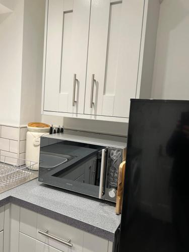 a microwave oven in a kitchen with white cabinets at Ground floor apartment, central location with free parking in Hereford