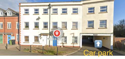 een groot wit gebouw met een parkeerplaats bij Ground floor apartment, central location with free parking in Hereford