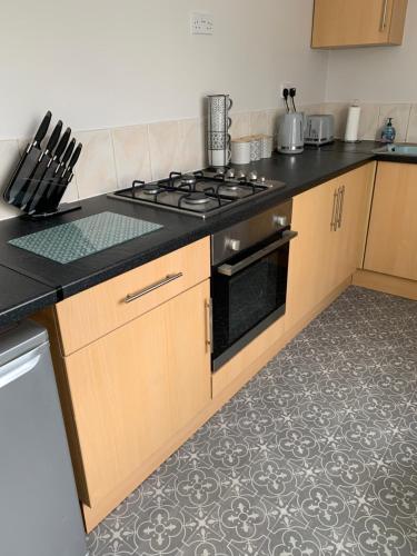 a kitchen with a stove and a counter top at The Greens Apartment in Farnworth