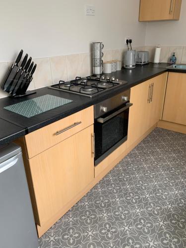 una cucina con piano cottura e piano di lavoro di The Greens Apartment a Farnworth