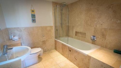 a bathroom with a tub and a toilet and a sink at Chesil Beach Lodge Burton Bradstock Dorset DT64RJ in Bridport