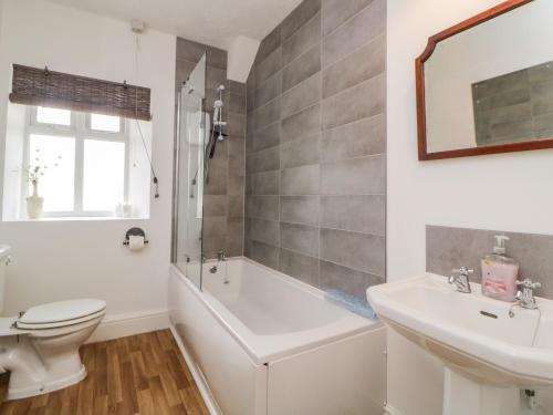 a bathroom with a tub and a toilet and a sink at Harmony House in Yelverton