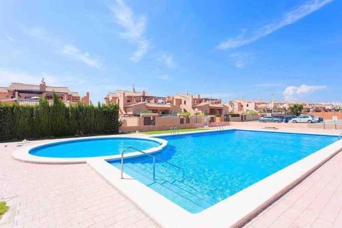 - une grande piscine bleue dans une cour avec des maisons dans l'établissement 2Bdr Apartment, à Torrevieja