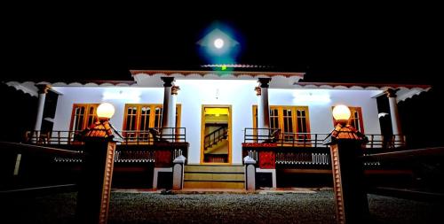 a white house at night with a green light at Kizhakkethottam Homestays-River View Villa in Pala
