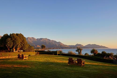 two benches in a park with a view of the water at Bendamere House Bed & Breakfast in Kaikoura