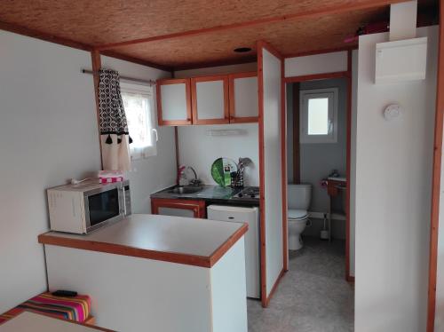 une petite cuisine avec un micro-ondes et un évier dans l'établissement Chalet simple au Camping L'Etruyere au lac, à La Tardière