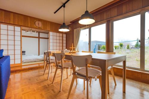a dining room with a table and chairs and windows at Furano Yukinko House in Furano