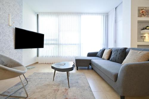 ein Wohnzimmer mit einem Sofa und einem TV in der Unterkunft Forever Young at Jean Jaures by HolyGuest in Tel Aviv