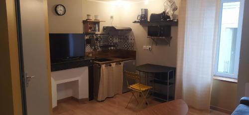 cocina con encimera, mesa y TV en Studio27, en Montredon-Labessonnié