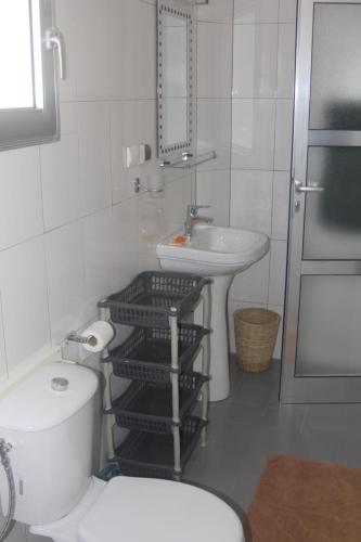 a white bathroom with a toilet and a sink at Le Margouillat in Toubakouta