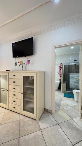 a room with a television on a wall with a bathroom at Espectacular Bajo Lirio in Calpe