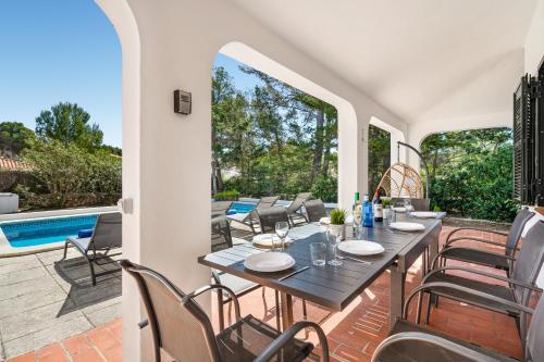 un patio con mesa y sillas y una piscina en Villa Misuco en Son Parc