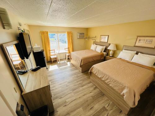 a hotel room with two beds and a flat screen tv at Coastal Inn - Ocean City in Ocean City