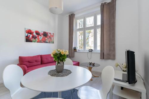 a living room with a white table and a pink couch at Kierunek Sopot Apartament DELUXE II Królowej Jadwigi 7 in Sopot